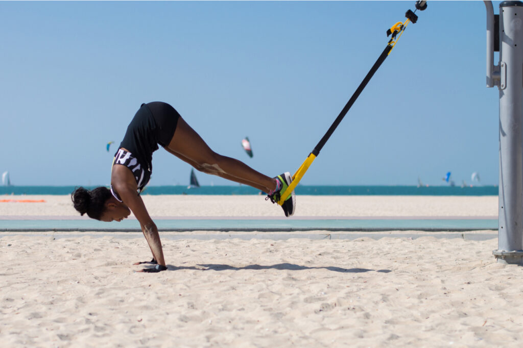 Woman performing difficult exercise using ropes for suspension training.