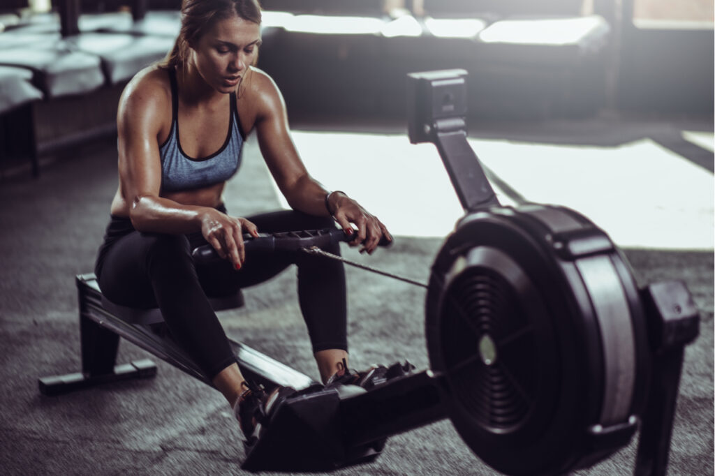 Young female athlete using rowing machine