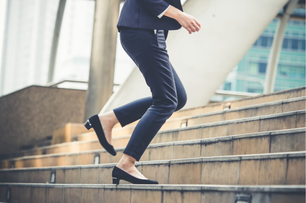 Close up legs of businesswoman fitness snacking walking stepping up stair in modern city.
