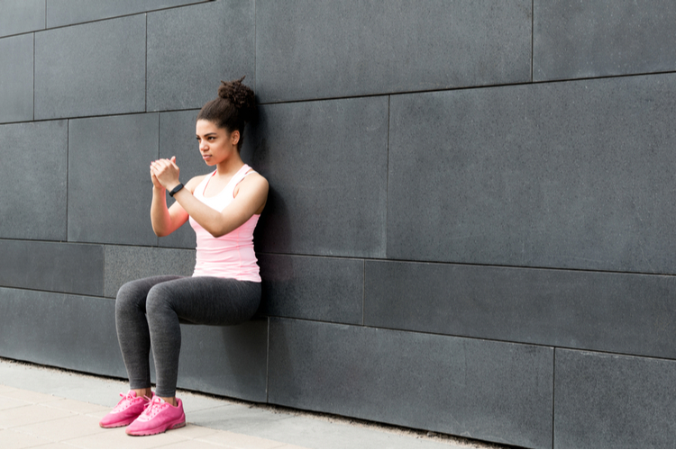 Athlete doing wall squat on city street.