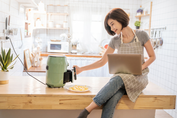 Woman cooking potato fried by instant vortex machine in kitchen home.
