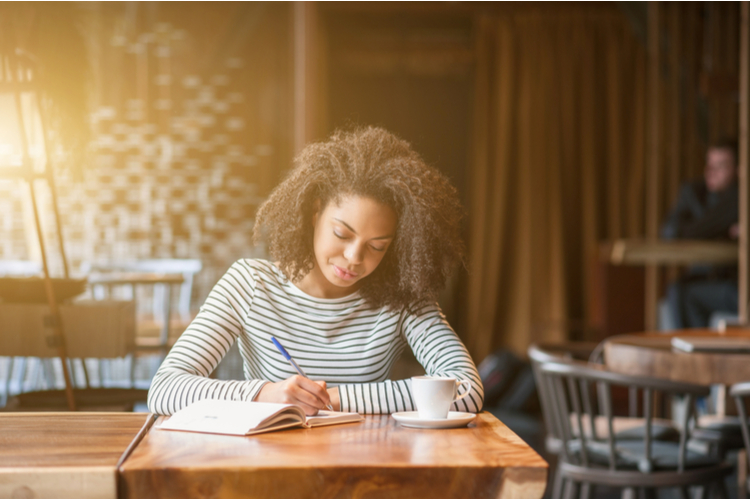 Woman journaling in cafeteria.