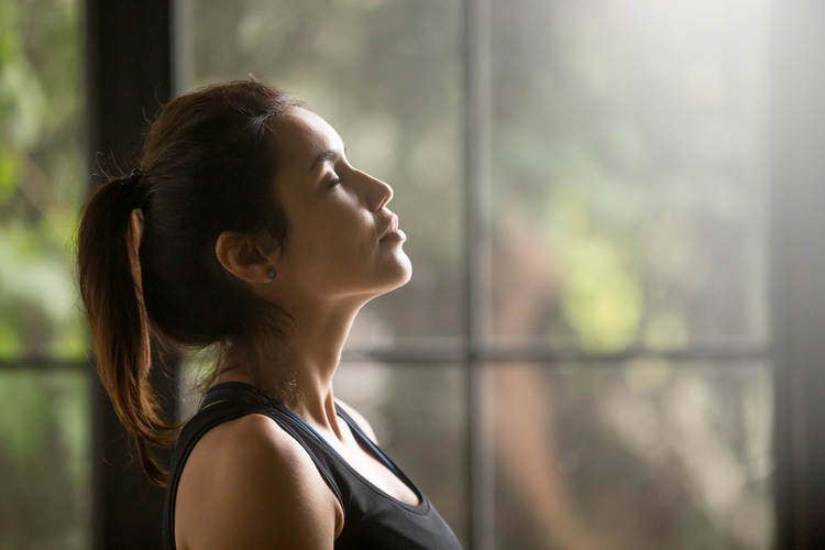 Yogi woman breathing fresh air with eyes closed.