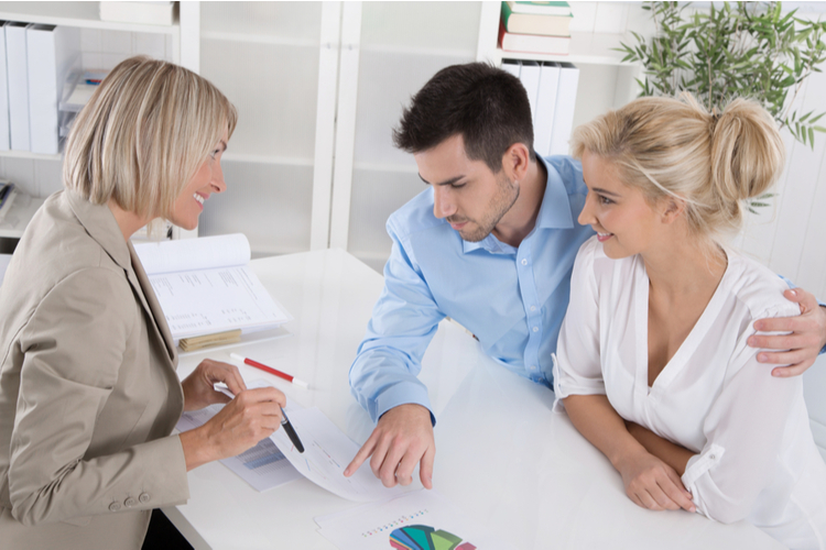 Young married couple sitting with an adviser at desk in a guidance or professional business meeting planning their provision for one's old age.