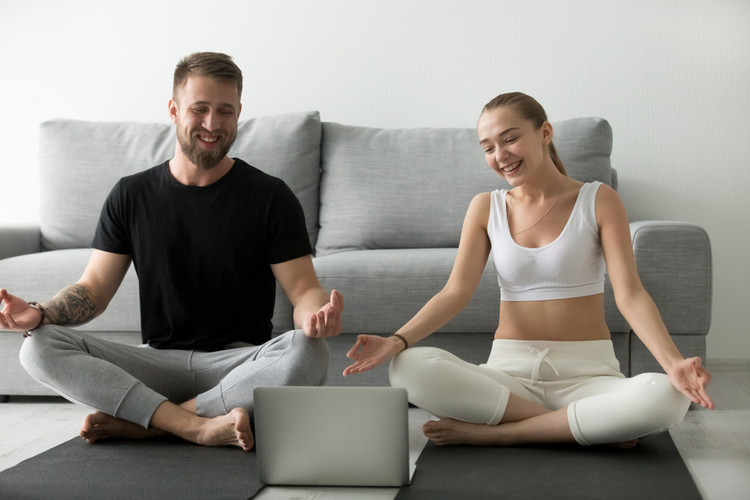 A couple doing yoga at home to stay healthy.