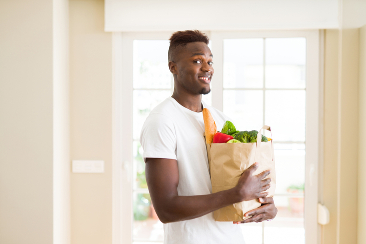Man holding paper bag full of healthy choices groceries as part of how to stop emotional eating.