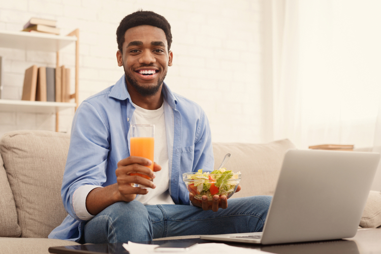 Man eating healthy lunch and watching movie on laptop at home.