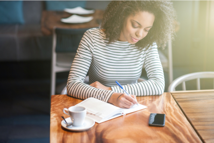 Woman writing on her journal in a cafe.