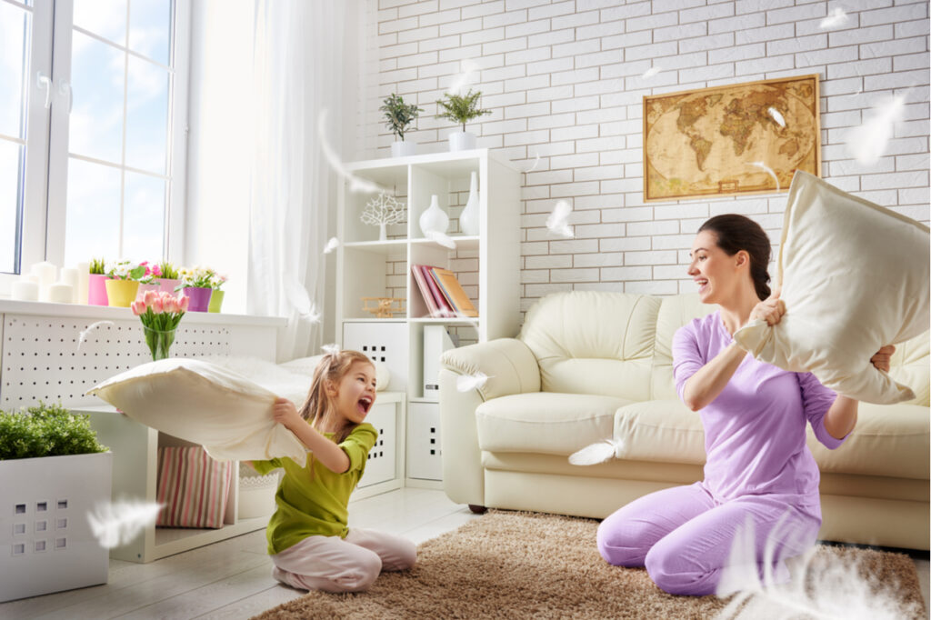 The mother and her child girl are fighting pillows.