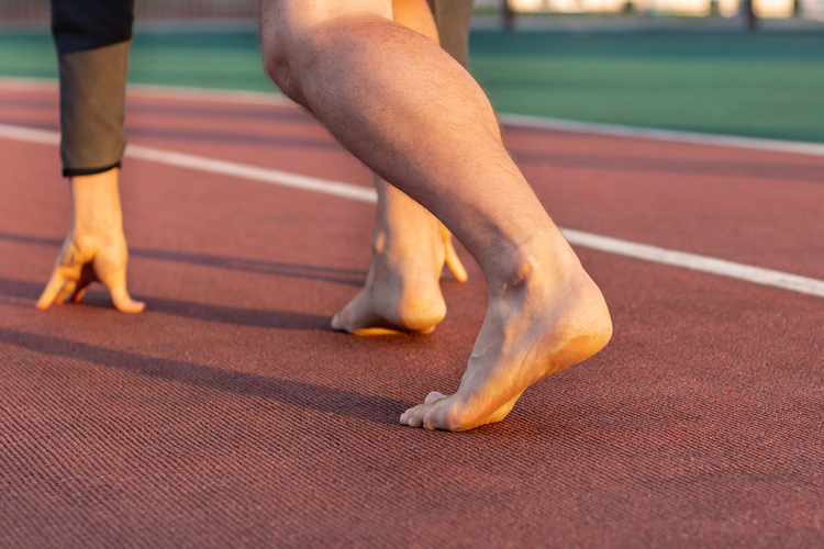 Athlete's legs on a starting position without shoes.