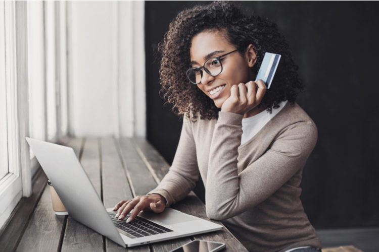 Young woman holding credit card and using laptop making payment online.