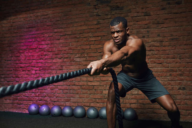 Cross fit coach stands with battle ropes proves that dynamic workout with ropes strengthening athlete's body.