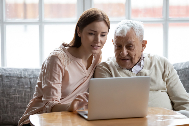 Grown-up daughter and old 80s father choose goods or services via internet or web surfing together at home.