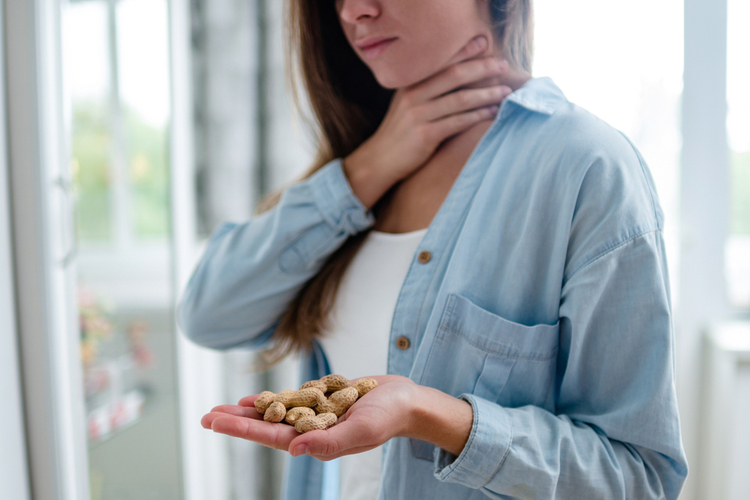Young woman suffers from choking and cough from food allergies after eating peanut.