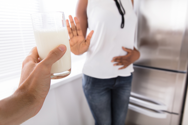 Woman rejecting a glass of milk offered by another person due to being lactose intolerant.