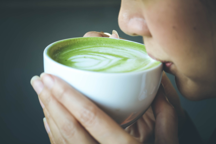 Close up of a woman drinking matcha latte.