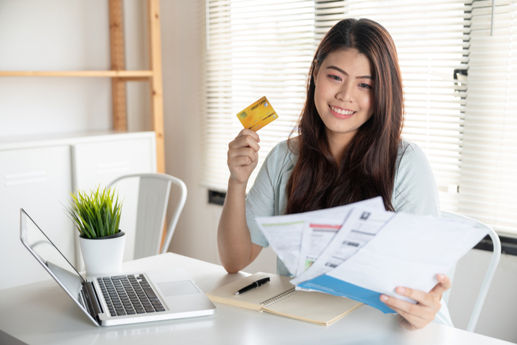 Woman smiling holding so many expenses bills such as electricity bill.