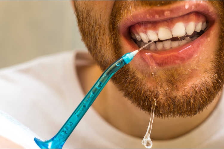 Man using a water flosser to floss his teeth.