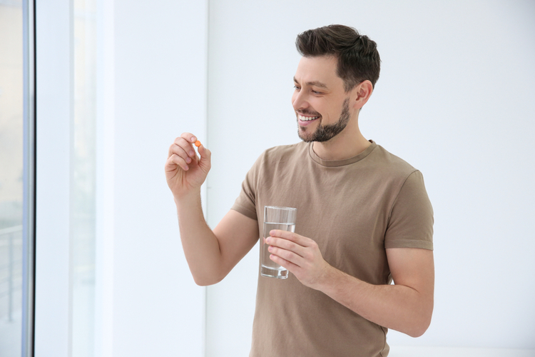 Young man taking vitamin indoors.