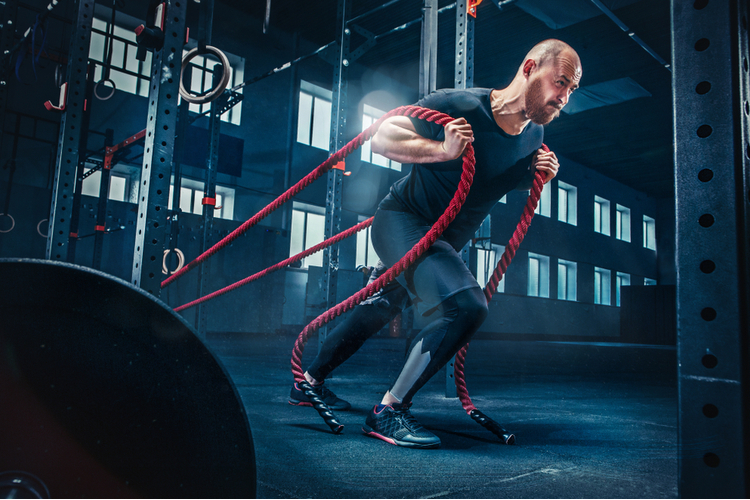 Men with battle rope battle ropes exercise in the fitness gym for mobility training.
