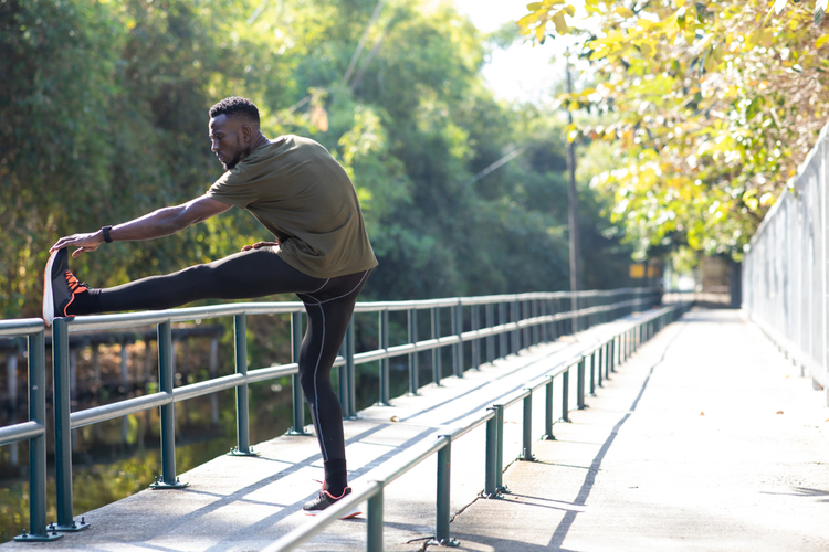 Man stretching exercise beside road in park at autumn morning which is one of the ways to reduce stress.