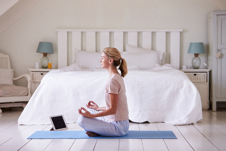 Woman with digital table using meditation app in bedroom.