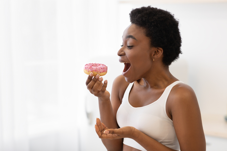 Woman on a cheat meal excited to take a bite at a donut.