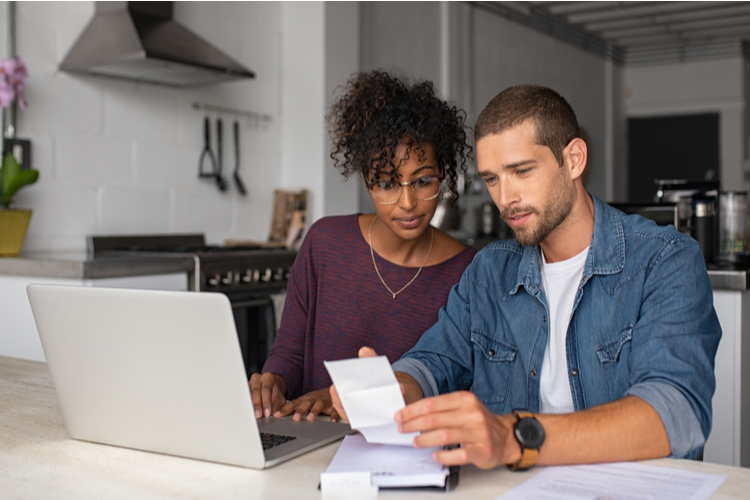 Couple sitting in front a computer while doing their budget and thinking of ideas to make money.
