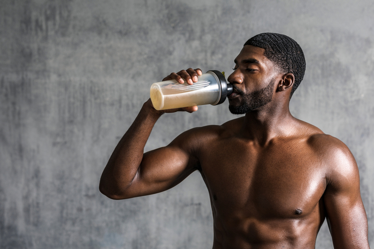 Muscular man drinking ladder plant protein after an intense workout.