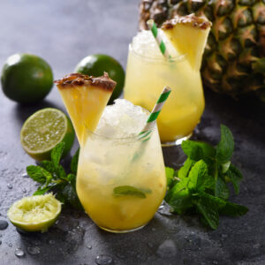 Cold pineapple cocktail with crushed ice, lime and mint, refreshing lemonade drink.