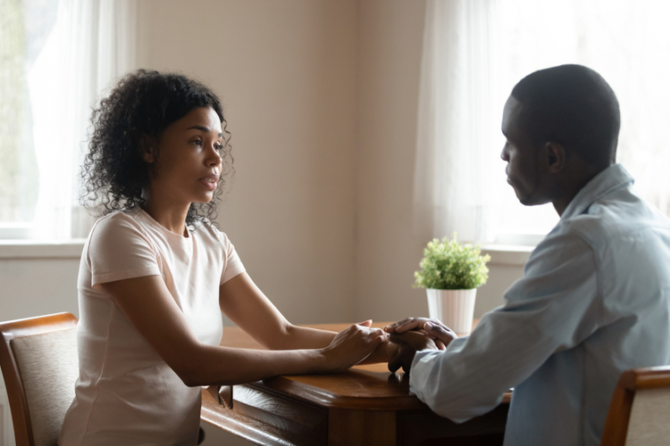 Couple sitting at table having heart-to-heart intimate straight talk.