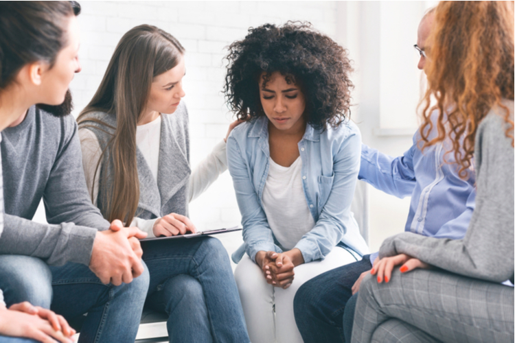 Understanding people giving support to depressed crying woman at group psychological treatment.