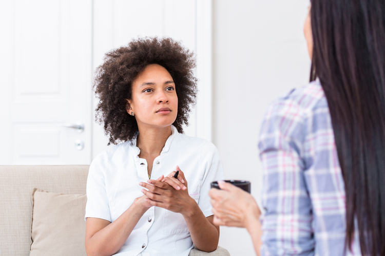 Psychologist listening to her patient and writing notes.