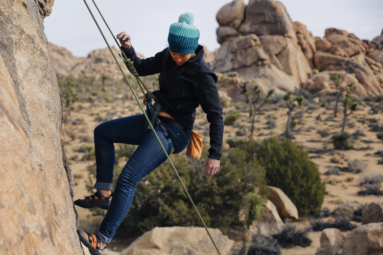 Young woman dressed for cold weather while rock climbing.