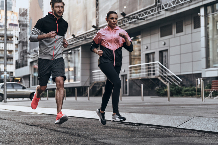 Full length of young couple in sport clothing running with runner's durable manual in mind.