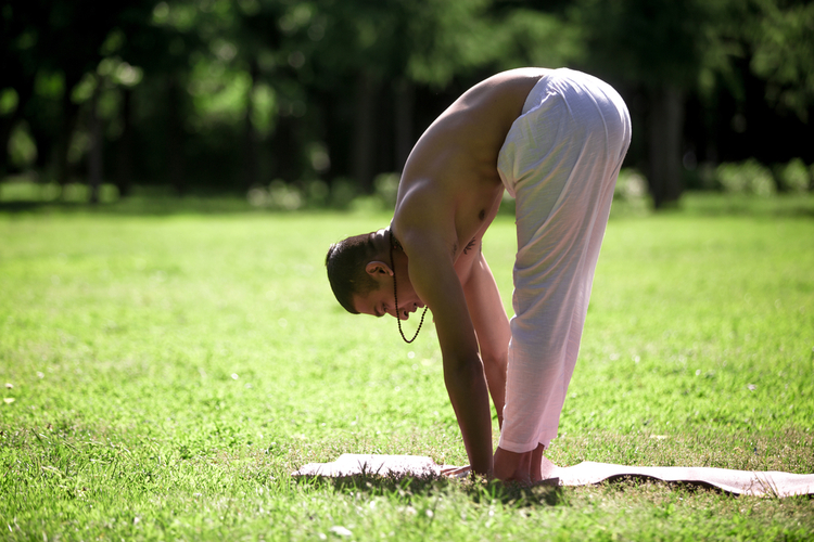 Profile of sporty young man exercising in park doing yoga.