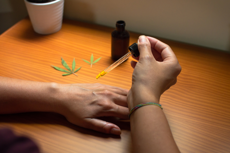 Woman pouring CBD oil on her hand to test the product.