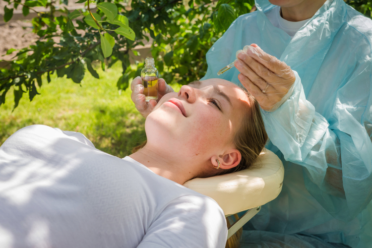 Cosmetologist takes care of the skin of a girl in nature with seabedee cbd skin care.