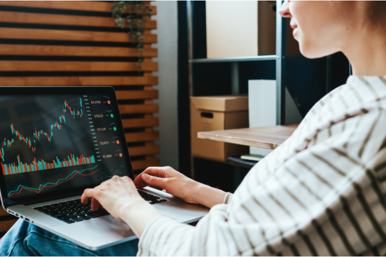 Woman investing in world stock market, using her laptop and m1 finance at home.