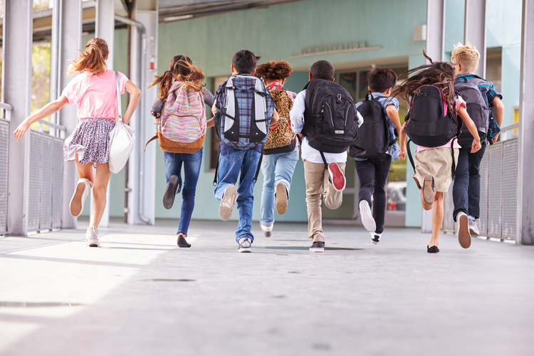 Group of elementary school kids running at school on national school backpack awareness day.