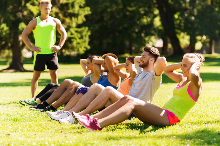 Group of people doing group exercise outdoors.
