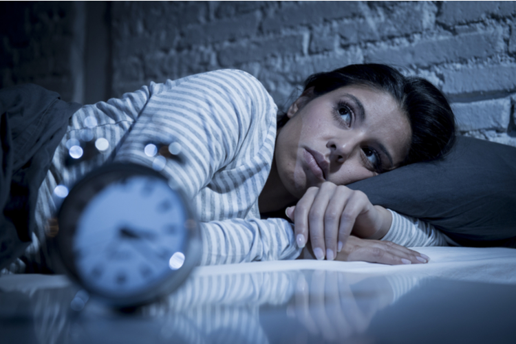 Woman lying in bed having problem sleeping, suffering from insomnia.