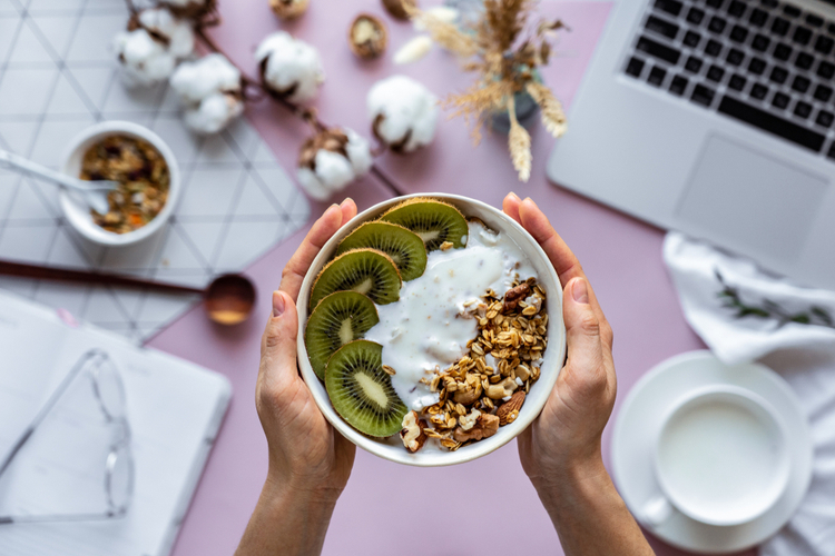A person holding a healthy breakfast bowl over work table background.