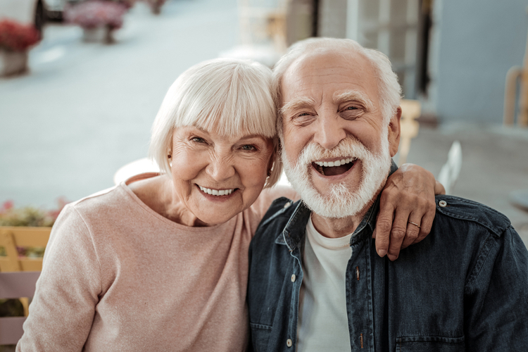 Joyful nice elderly couple smiling while being in a great mood after world smile day activities.