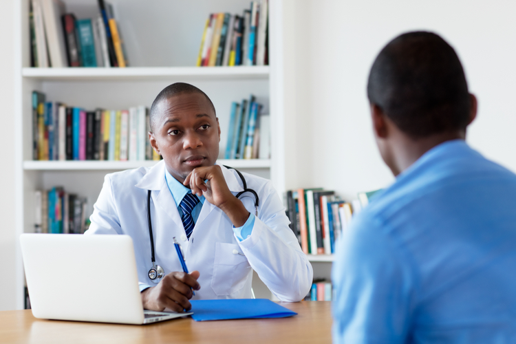 African American Doctor With Male Patient at Hospital