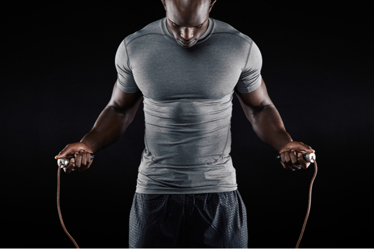 Muscular Man Skipping Rope. Portrait of Muscular Young Man Exercising With Jumping Rope on Black Background