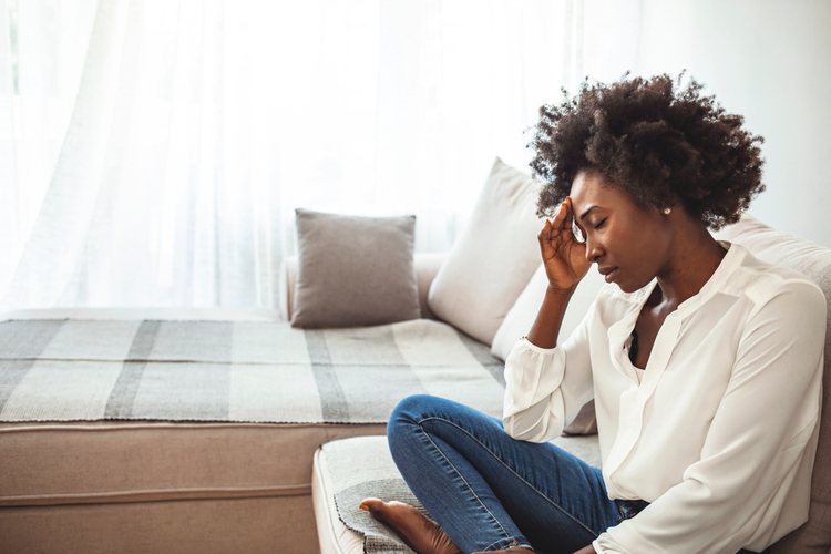 Woman sitting on a couch needing to know how to cope with anxiety.
