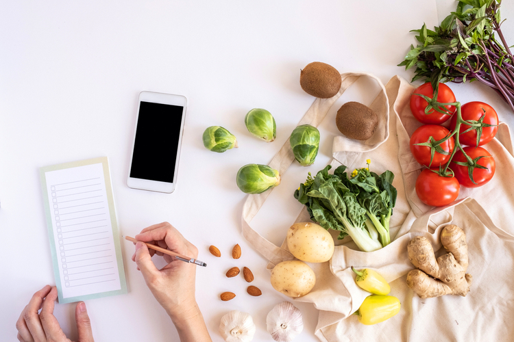 Woman listing things for grocery shopping avoiding unwanted extra items.