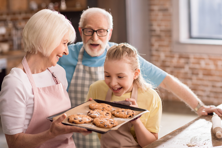 Grandparents and grandchild looking at tray with delicious cookies.