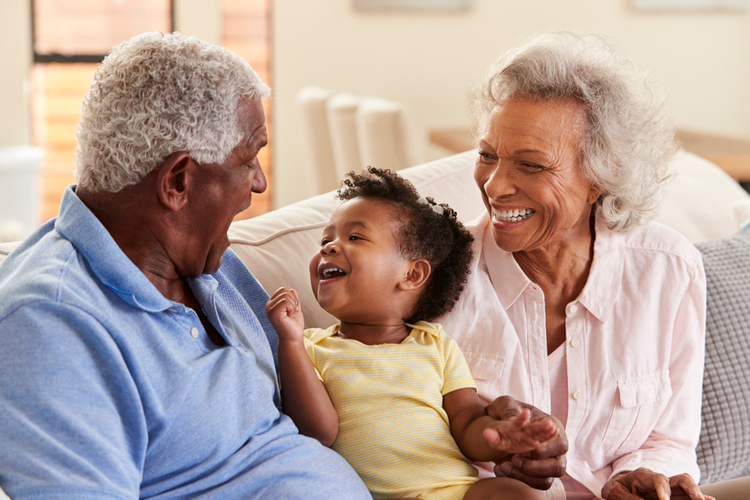 Grandparents sitting on the sofa playing with their granddaughter knowing when is grandparents' day.